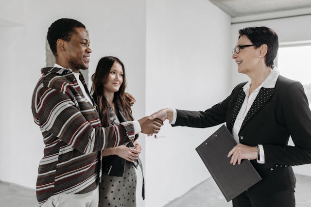 A woman shaking hands with a man standing next to a girl